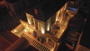 An aerial view of a building with a courtyard, stone walls, and a small Christmas tree. - Fedora Alacati (Cesme)