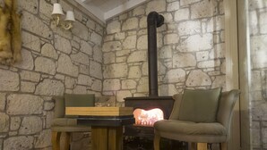 A cozy room with a stone wall, a fireplace, a table, and two chairs. - Fedora Alacati (Cesme)