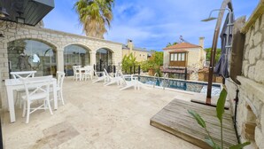 A pool area with white lounge chairs and a stone patio. - Fedora Alacati (Cesme)