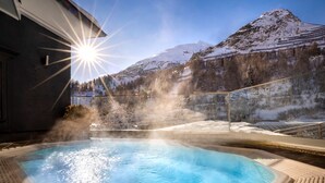A hot tub with a mountain backdrop, surrounded by a wooden deck and a glass enclosure. - Kesselspitze Hotel & Chalet, Valamar Collection (Tweng)