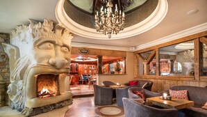 A lobby with a stone fireplace, modern seating, and a chandelier. - Kesselspitze Hotel & Chalet, Valamar Collection (Tweng)