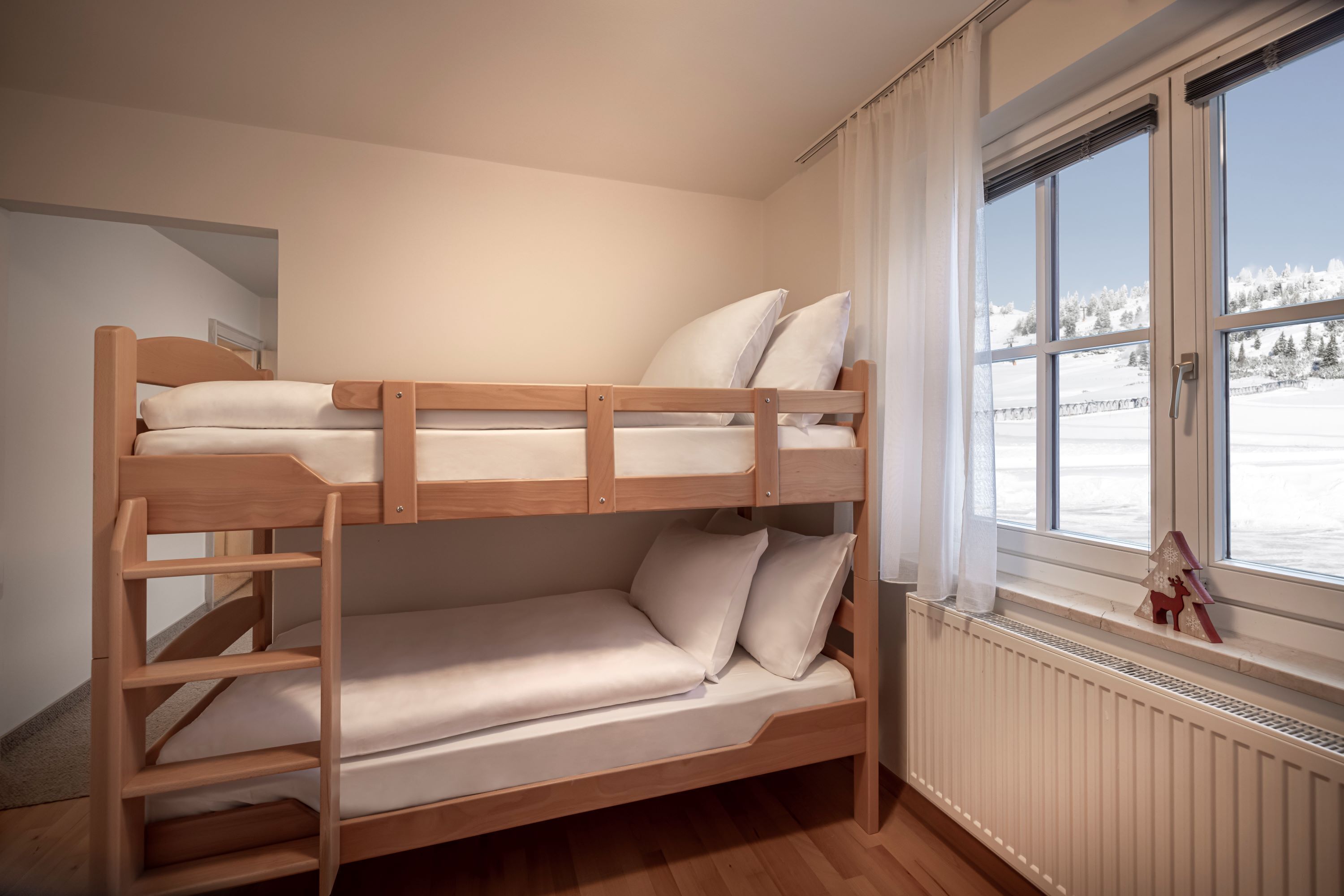 A bunk bed with a window view of a snowy landscape.