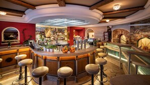 A bar area with stools, a counter, and a stone wall. - Kesselspitze Hotel & Chalet, Valamar Collection (Tweng)