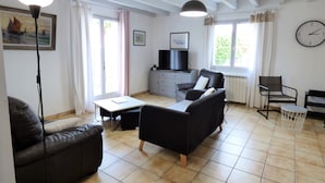 Un salon comprenant un canapé, une table basse, un téléviseur et un coin repas avec une chaise et une petite table.