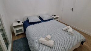 Une chambre à coucher avec un lit, une table de chevet, une commode, une porte et une fenêtre.