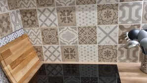 Une cuisine dotée d’une plaque de cuisson à induction noire, d’une planche à découper en bois et d’un crédence décorée.