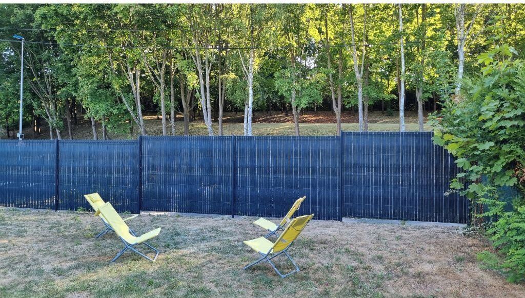 A fenced backyard with two yellow lawn chairs.