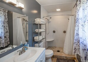 Een bad/douchecombinatie, een haardroger, handdoeken, zeep