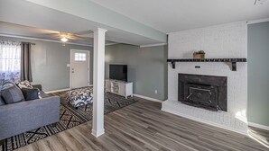 A living room with a fireplace, a sofa, a TV, and a patterned rug. - Cozy Home off I-85, 35 minutes from NC and SC border (Spartanburg)
