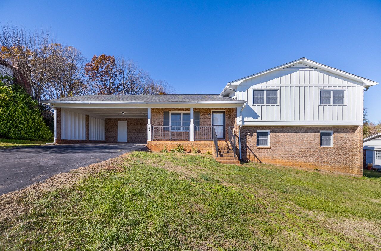 A two-story house with a garage, brick exterior, and a covered front porch.