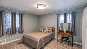 A bedroom with a bed, a vanity with a mirror, and curtains on the windows. - Cozy Home off I-85, 35 minutes from NC and SC border (Spartanburg)