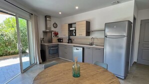 Een moderne keuken met een ronde houten tafel, blauwe stoelen en een roestvrijstalen koelkast.