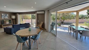 Een moderne woonkamer met een ronde houten tafel, blauwe stoelen, een bank en een televisie.