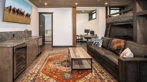 A cozy living area with a sofa, a coffee table, a rug, and a painting of horses on the wall.