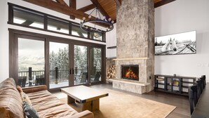 A spacious living room with a stone fireplace, large windows, and a cozy seating area.