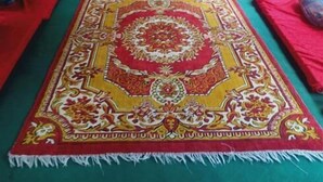 A corridor with a long, ornate carpet and red cushions along the sides.