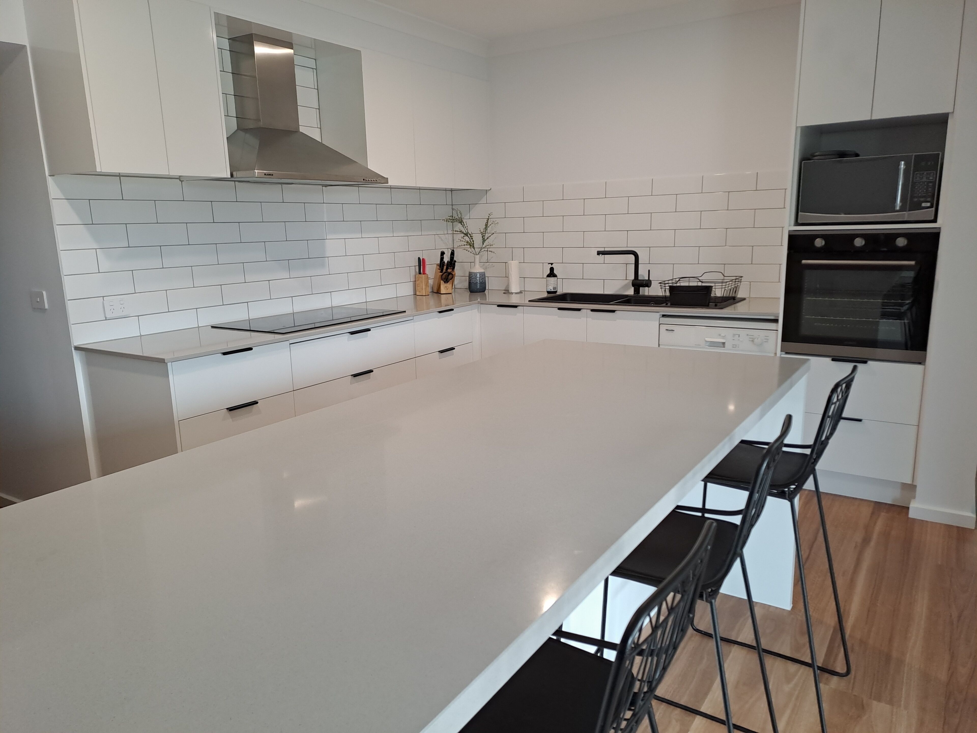 Kitchen with large island, dishwasher, cooktop, oven, and a walk-in pantry.