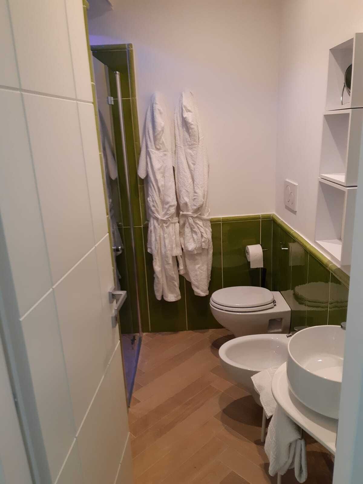 Une salle de bain avec deux toilettes, un lavabo et un miroir. Des serviettes blanches sont suspendues à un porte-serviettes.