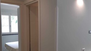 A modern, minimalist bedroom with a bed, a walk-in closet, and a hallway leading to a bathroom. - Apartament CARPEDIEM in the Historical center, accessible by 59 steps At 650mt from the Cathedral (Amalfi)