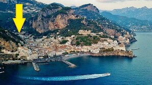 A coastal town with buildings along the waterfront, a pier, and mountainous terrain in the background. - Apartament CARPEDIEM in the Historical center, accessible by 59 steps At 650mt from the Cathedral (Amalfi)