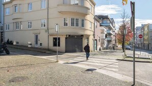 Un edificio curvo con entrada a nivel de la calle, un paso de peatones y una señal de prohibido girar a la derecha.