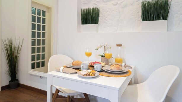 Una mesa de desayuno con platos, tazas y vasos de jugo.