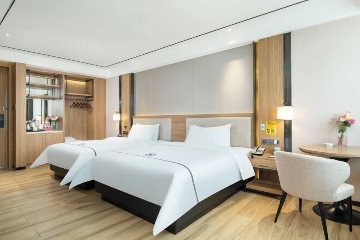 A hotel room with a large bed, a desk, and a chair.