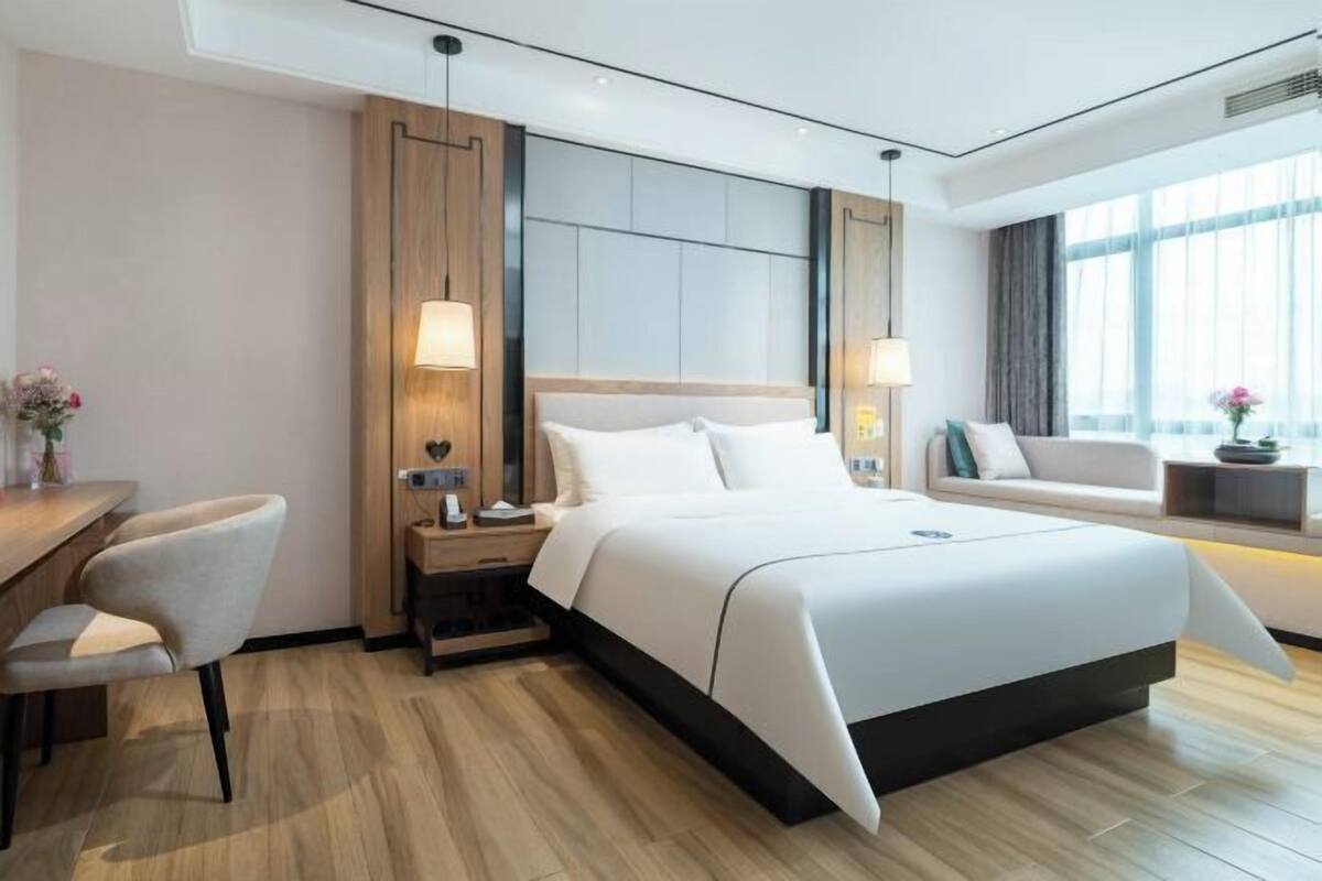 A modern hotel room with a large bed, a desk, and a sofa.