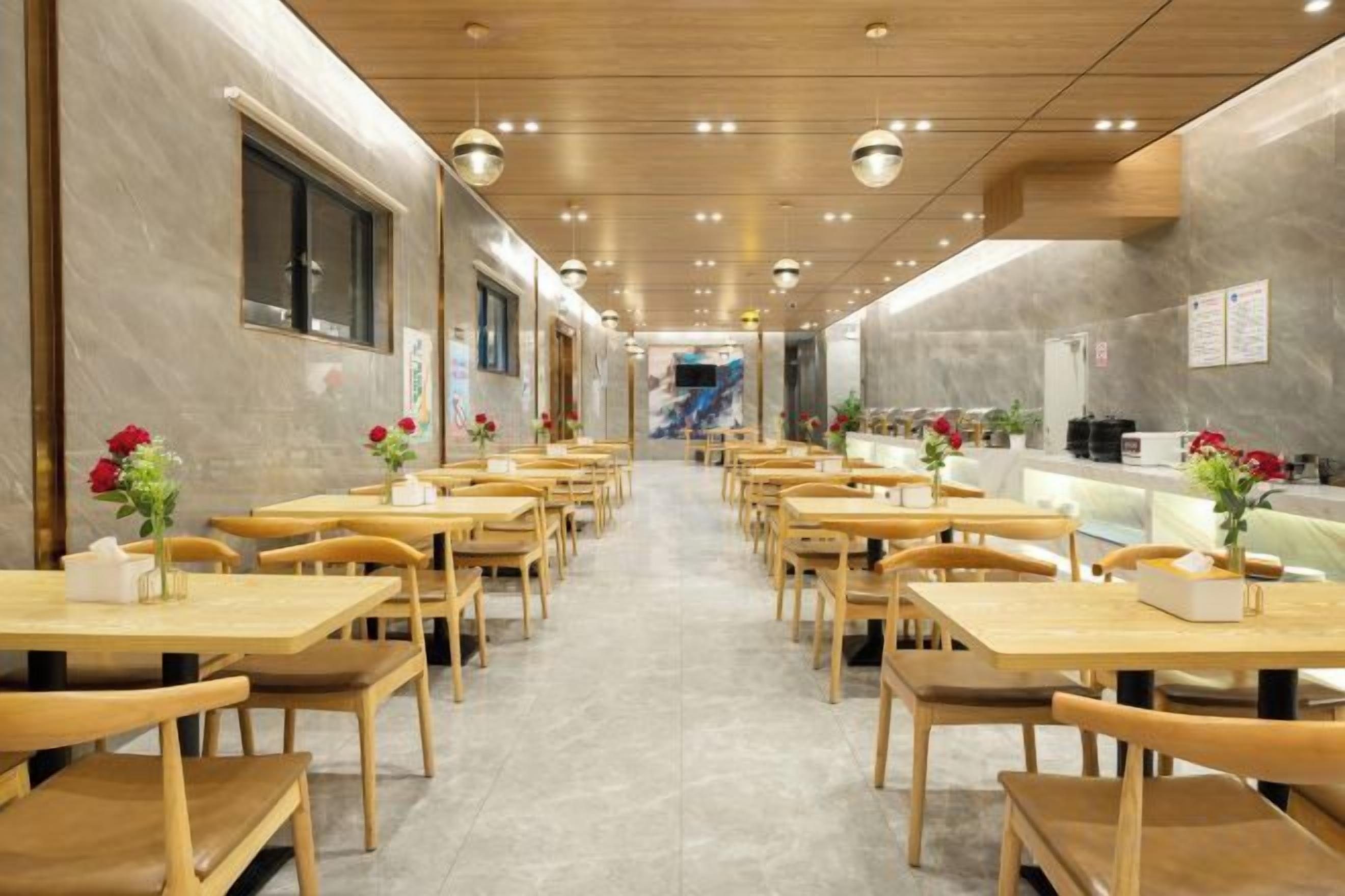 A restaurant with wooden tables and chairs, a counter, and a view of the street.