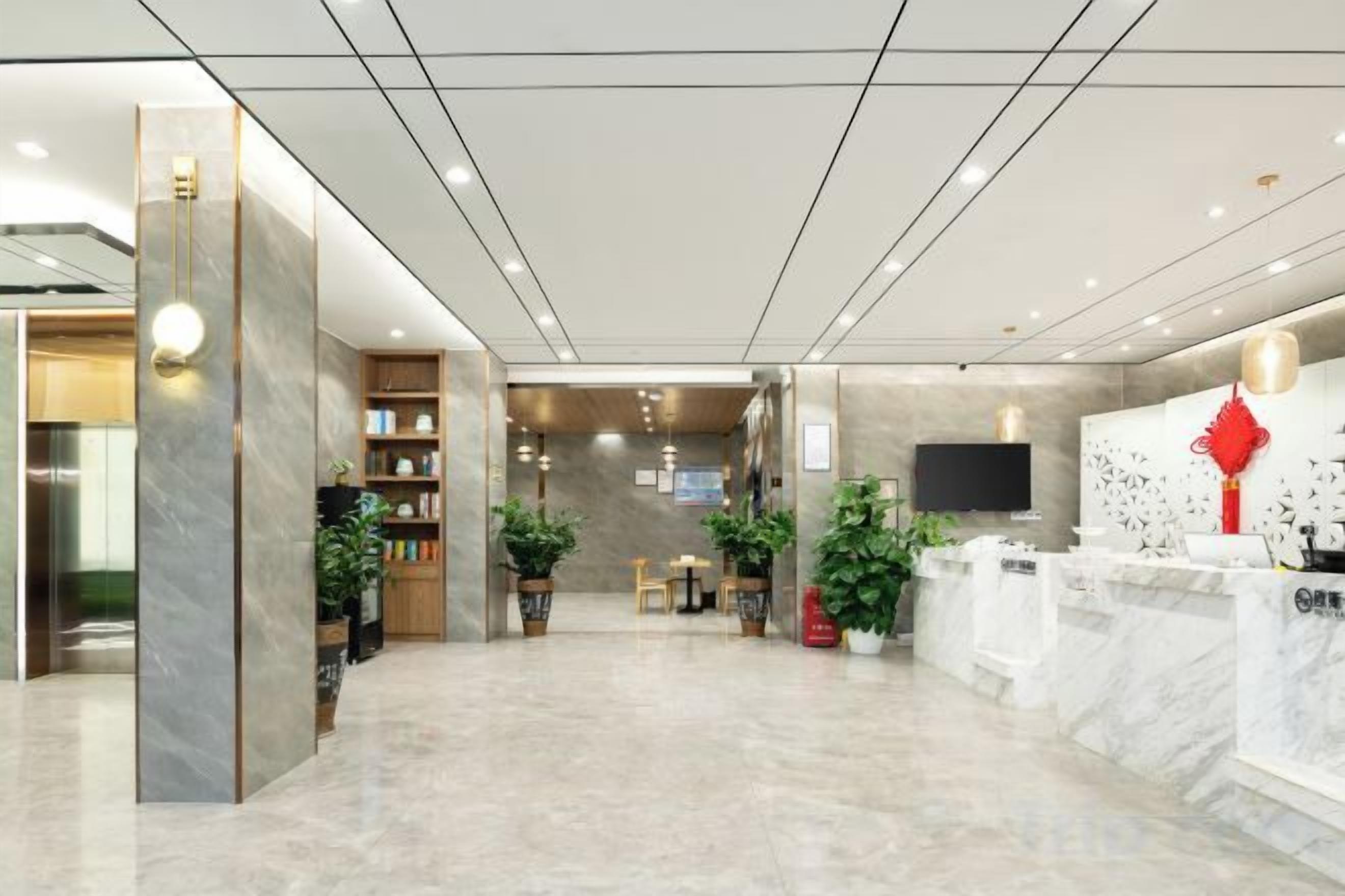 A hotel lobby with a reception desk, seating area, and a wall-mounted TV.