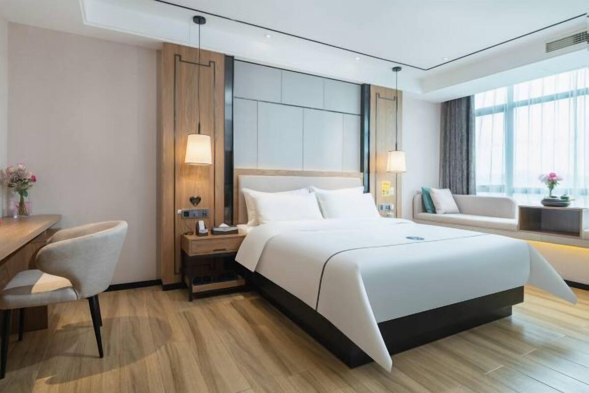 A modern hotel room with a large bed, a desk, and a chair.