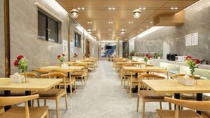 Een restaurant met houten tafels en stoelen, een lange toonbank en een betegelde vloer.