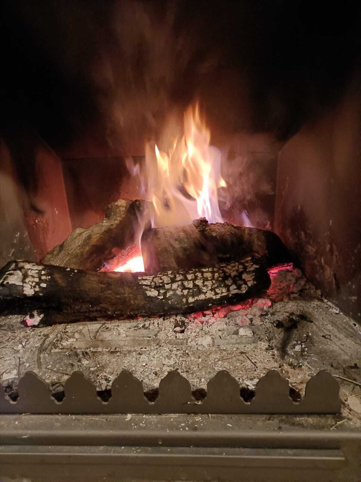 Een open haard met brandende blokken hout en vlammen.