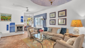 A living room with a fireplace, a sofa, a coffee table, and a chandelier. - Villa Arin - Beachside Family Home (Estepona)