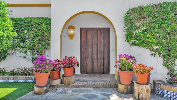 A courtyard with a wooden door, potted plants, and a tiled floor. - Villa Arin - Beachside Family Home (Estepona)