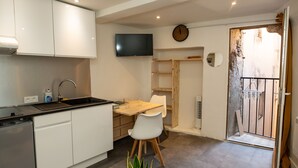 Eine kompakte Küche mit weißen Schränken, einem integrierten Geschirrspüler und einem Holztisch mit zwei Stühlen.