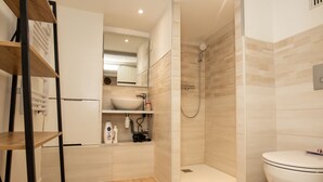 Ein modernes Badezimmer mit Dusche, Toilette, Waschbecken und Regalen.