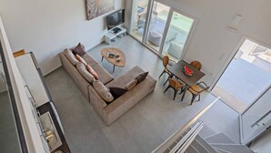 Een moderne woonkamer met een bank, salontafel en eethoek.