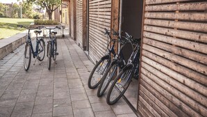 Des vélos sont garés devant un bâtiment dont la façade est en bois et qui est doté d’un trottoir dallé.