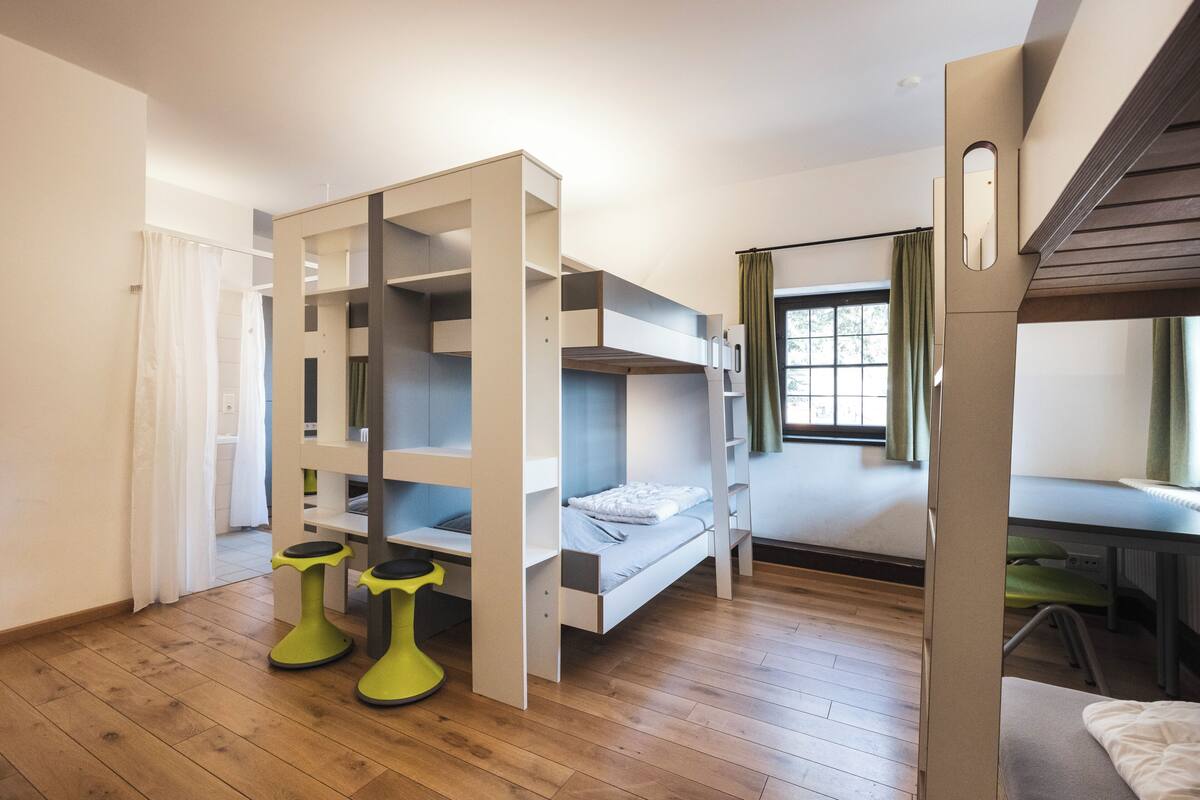 Une chambre de dortoir avec des lits superposés, un bureau et une chaise.
