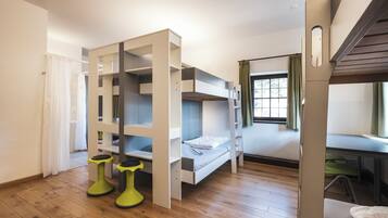 Une chambre de dortoir avec des lits superposés, un bureau et une chaise.