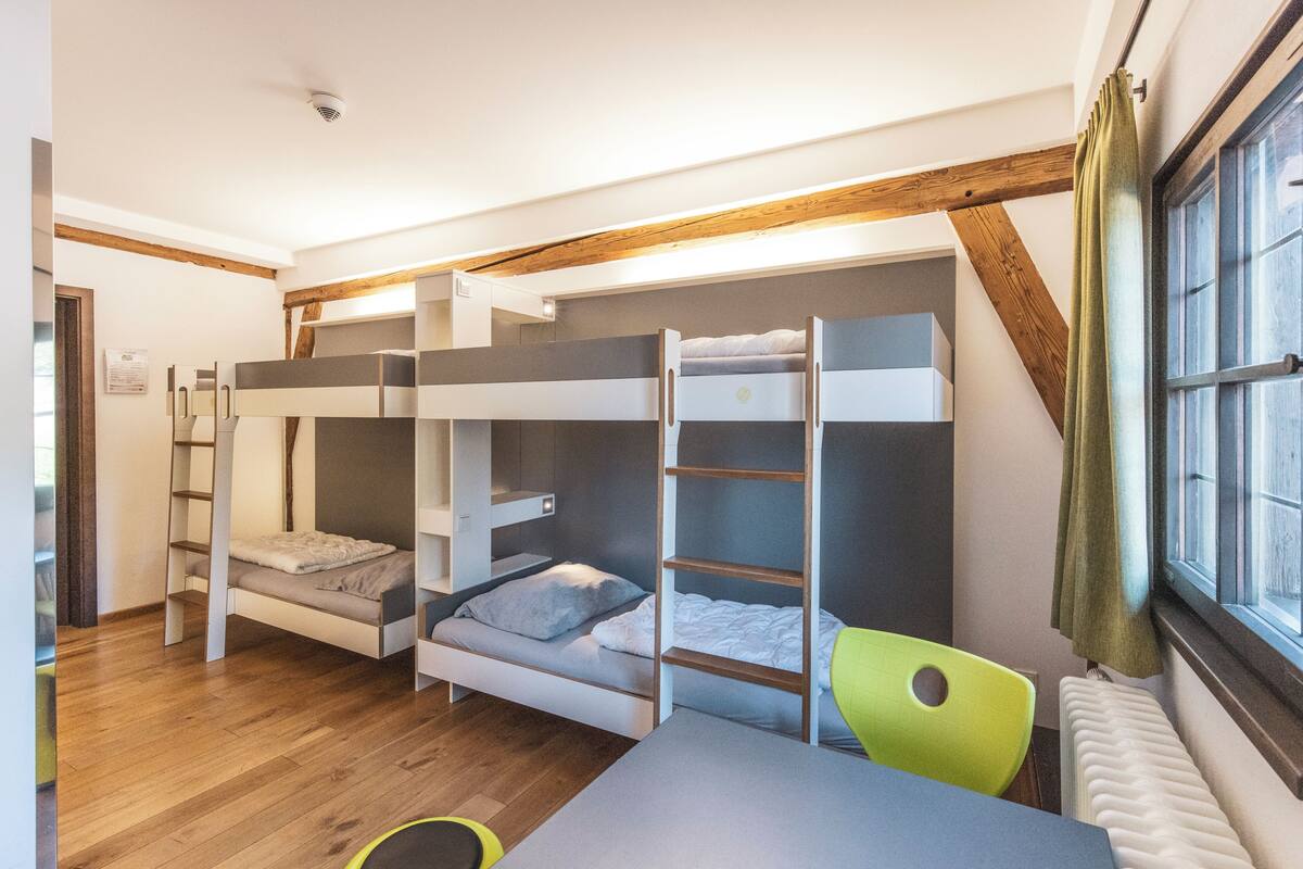 Une chambre avec des lits superposés, un bureau et une chaise.