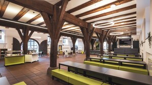 Un vaste espace dédié à la salle à manger, doté de hauts plafonds, de poutres apparentes en bois et d’appareils d’éclairage circulaires modernes.
