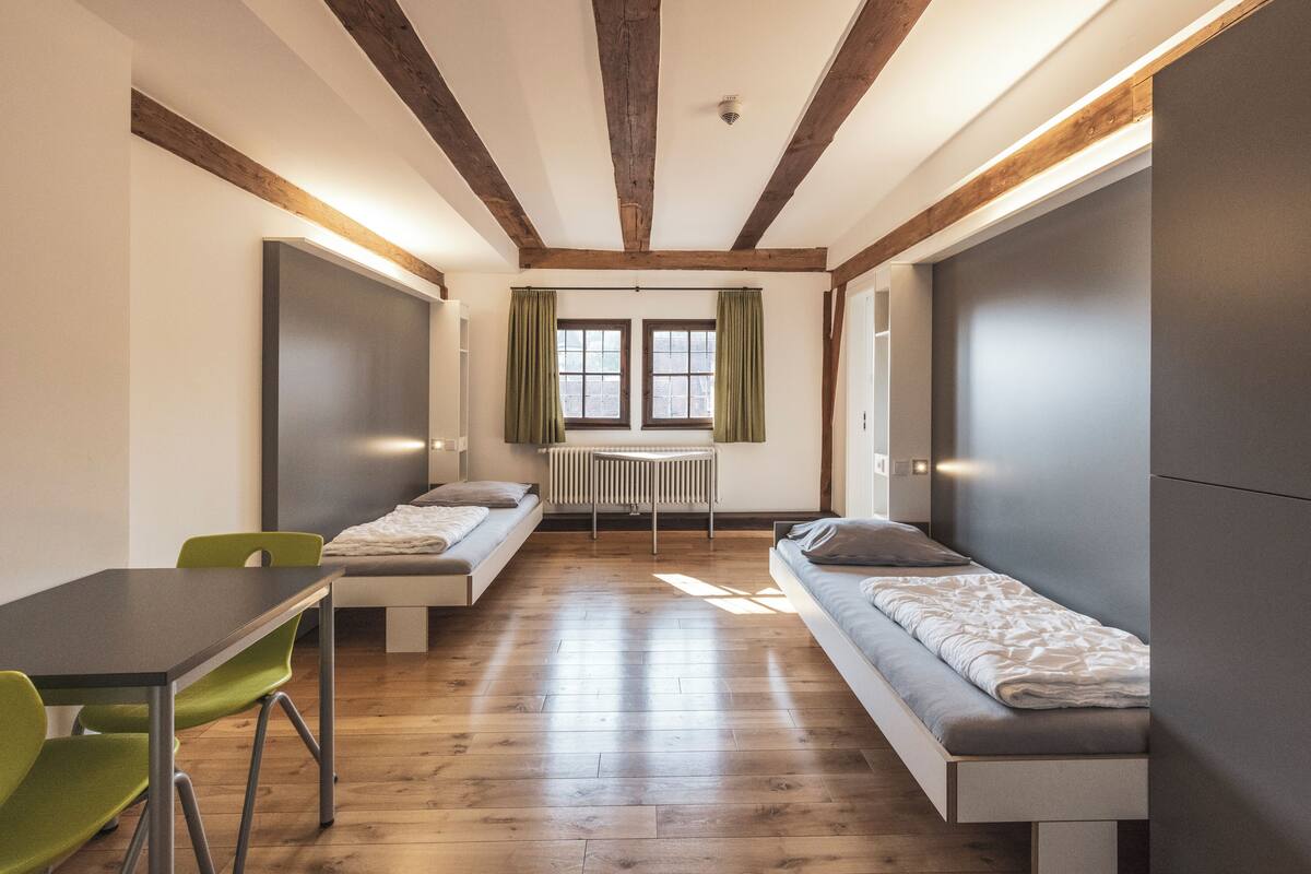 Une chambre moderne avec un plafond en bois, un lit, une table et une chaise.