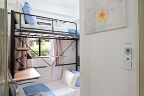 A bunk bed room with a desk, a lamp, and a window with curtains. - Delightful Apartment Holiday Rental (Davao City)