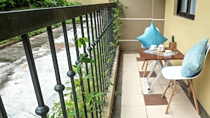 A balcony with a metal railing, a table with a chair, and a small potted plant. - Delightful Apartment Holiday Rental (Davao City)