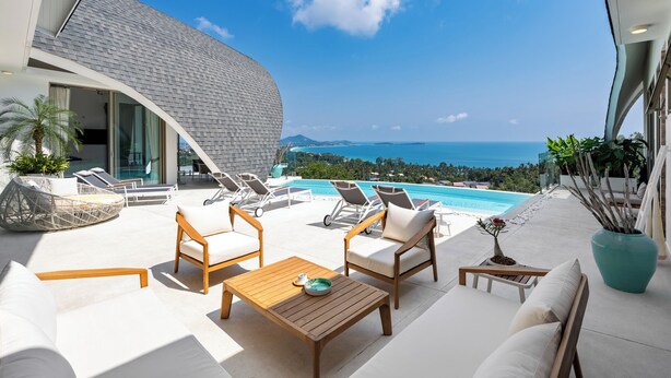 Un espace de détente extérieur moderne, doté d’une piscine, de chaises longues et offrant une vue sur l’océan.