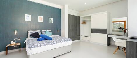 A modern bedroom with a bed, bedside table, wardrobe, desk, chair, and a large window.