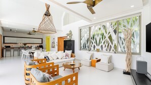Un vaste espace de vie comprenant un ensemble de canapés, des chaises en bois, une table basse et une grande fenêtre offrant une vue dégagée.