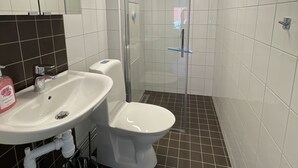 Un baño con lavamanos blanco, inodoro y ducha con mampara de vidrio.
